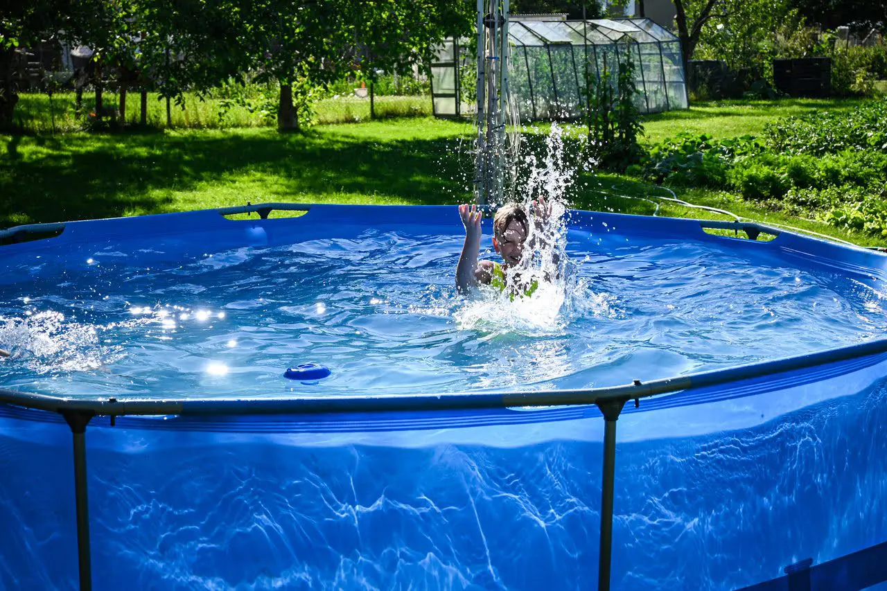 A person in the water of an above ground pool.