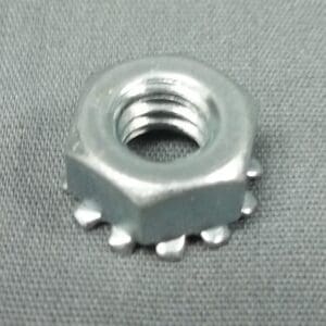 Metal nut with serrated edge on fabric.