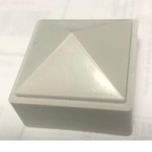Gray square plastic object with pyramid top.